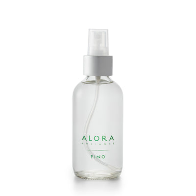Small, glass spray bottle with "Alora Ambiance" and "Pino" written on the front in green font, bottle is filled with clear liquid fragrance