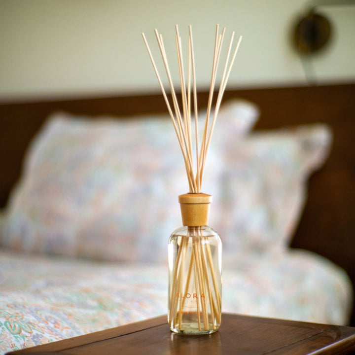 Arancia diffuser on a nightstand next to a bed covered in a paisley patterned quilt