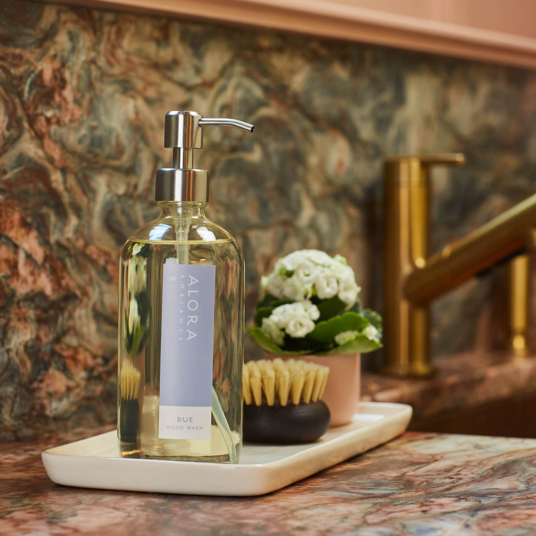 Due hand wash bottle on a white porcelain tray next kitchen sink.