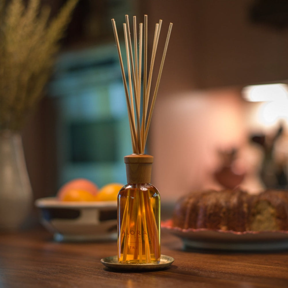 Tre reed diffuser in front of bundt cake and a bowl of oranges