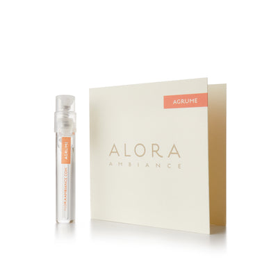 Small clear plastic vial that says “Alora Ambiance” and “Agrume” next to a tan card that also says “Alora Ambiance" and “Agrume”