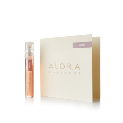 Small clear plastic vial filled with liquid fragrance that says “Alora Ambiance” and “Uno” next to a tan card that also says “Alora Ambiance" and “Uno”